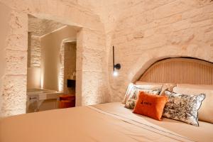 - une chambre avec un grand lit et un mur en pierre dans l'établissement Naiira Luxury Trullo, à Alberobello