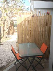 une table en verre et deux chaises à côté d'une clôture dans l'établissement Avocado Studio, à Nouméa