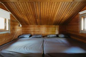 a bed in a cabin with a wooden ceiling at Matildanjärven Lippa in Mathildedal