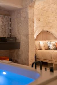 - une salle de bains avec baignoire et un lit dans une chambre dans l'établissement Naiira Luxury Trullo, à Alberobello