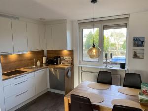een keuken met witte kasten en een tafel en een raam bij Villa Sunlight Comfortable Vacation Home in Makkum