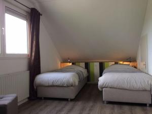 2 bedden in een zolderkamer met een raam bij Villa Sunlight Comfortable Vacation Home in Makkum