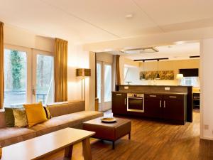 a living room with a couch and a kitchen at Spacious Retreat, Vlagtwedde in Vlagtwedde
