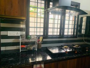 una cocina con encimera negra y algunas ventanas en Joann Serviced Apartment en Thiruvalla