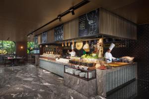 a restaurant with a counter with people preparing food at HUALUXE Xi'an Tanghua, an IHG Hotel in Xi'an