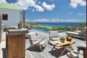 a patio with a table and chairs and the ocean at Villa Vogue 5 Bedroom Villa in Saint Barthelemy