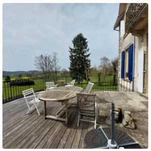 una terraza de madera con mesa y sillas. en Le Clos Saint Roch, en Saint-Amand-Jartoudeix