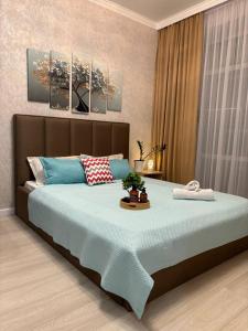 1 dormitorio con 1 cama grande con almohadas azules en ЖК ALPAMYS, en Astana