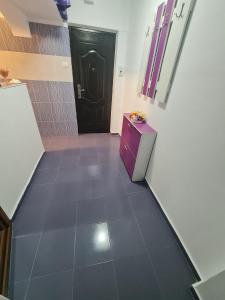 a hallway with a black door and a tile floor at Apartament Eric in Mangalia +2 photos