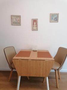 a wooden table with two chairs in front of a wall at Ferienwohnung in Veitshöchheim in Veitshöchheim