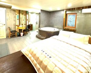 a bedroom with a large bed and a bath tub at Yeonsan In Hotel in Busan