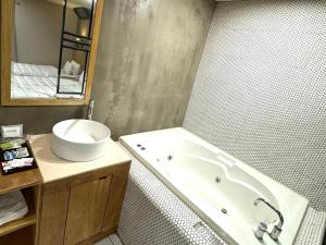 a bathroom with a bath tub and a sink at Yeonsan In Hotel in Busan