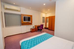 um quarto de hotel com uma cama e uma televisão em TIYANA INN em Nagpur