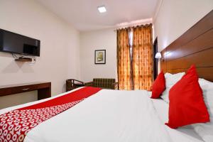 um quarto com uma grande cama branca com almofadas vermelhas em Super OYO Jaipur Casa Near Sawai Man Singh Stadium em Jaipur