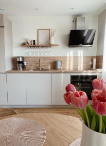 una cucina con armadi bianchi e un vaso di tulipani rossi di NEU Ferienwohnung am Kloster, ländliche Idylle mit der ganzen Familie a Beuren