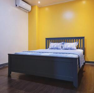 1 dormitorio con cama azul y pared amarilla en Sensi Stay en Garapan