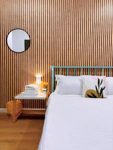 1 dormitorio con cama blanca y pared de madera en Muji Homestay Ria Heights Tawau, en Tawau