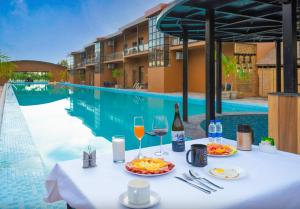 een tafel met eten en wijnglazen naast een zwembad bij Vanya - Urban Villa and Resorts in Belparāo