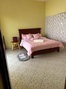 Schlafzimmer mit einem Bett mit rosa Bettwäsche und einem Tisch in der Unterkunft Dangotte Residence Lounge in Kabale