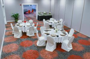 een kamer met witte tafels en witte stoelen en een tafel bij Holiday Inn Mobile West I-10, an IHG Hotel in Tillmans Corner