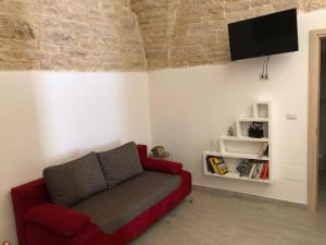 een woonkamer met een rode bank en een flatscreen-tv bij La piccola casa di Tania in via Fiore in Terlizzi