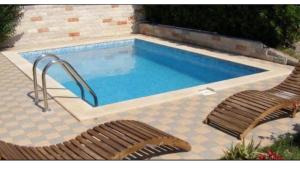 a swimming pool with two chairs at Hestia Apartments in Rovinj