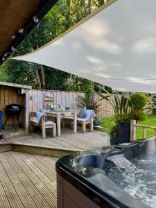 a backyard deck with a table and a grill at The Lodge@Tyddyn Ucha in Caernarfon