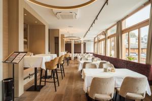 a restaurant with white tables and chairs and windows at Heritage Hotel Hallstatt in Hallstatt +37 photos