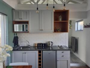 a kitchen with white cabinets and a sink at Fevertree cottage in Bloemfontein