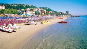 a beach with chairs and boats on the sand at Bassa Marea in Grottammare