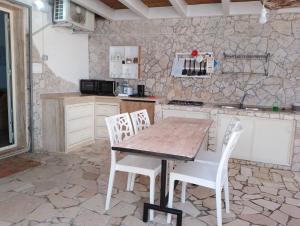 a kitchen with a wooden table and white chairs at Finestre Sul Mare Salento - CasaVacanza in Punta Prosciutto