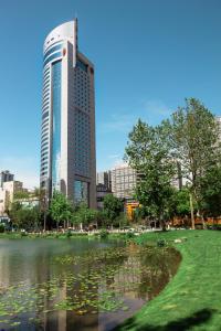 a tall building with a pond in front of a city at Sheraton Chengdu Lido Hotel in Chengdu