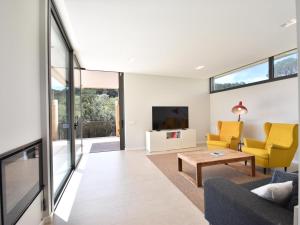 a living room with yellow chairs and a tv at Villa Clarisse in Tamariu