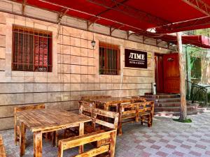 a group of wooden tables and benches in front of a building at Time Hotel & Tours in Yerevan