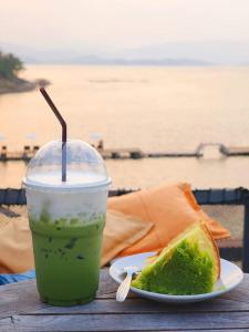 een drankje en een stuk brood op een tafel met de oceaan bij ภูไพรเลค รีสอร์ท in Ban Wang Khun Knachen