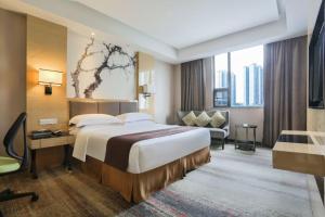 a hotel room with a large bed and a chair at MIZPARTON HOTEL - Heshan New Town in Jiangmen