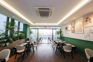 a restaurant with tables and chairs and a green wall at 3T Hotel Hanoi in Hanoi