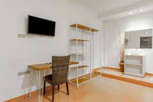 a room with a desk and a television on a wall at Capital O 93944 Geweka Homestay in Jimbaran