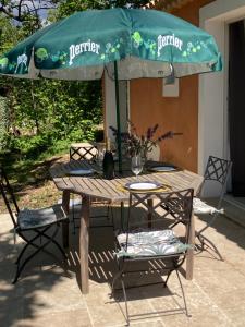 einen Picknicktisch mit einem grünen Sonnenschirm und Stühlen in der Unterkunft Guest house in Le Rouret
