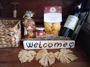 a basket with a welcome sign and some food and wine at Casa delle foglie sussurranti in Asti