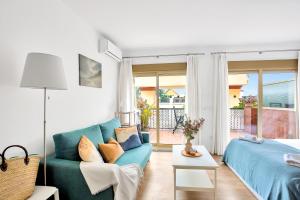 Romana Playa beach apartment 723 in Elviria, Marbella في مربلة: غرفة معيشة مع أريكة زرقاء وسرير