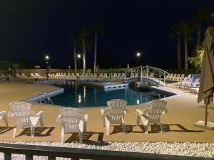 a group of chairs sitting around a pool at night at La petite Camargue in Le Grau-du-Roi