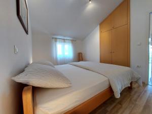a bedroom with a large bed with white sheets and a window at Apartment Dumica in Malinska