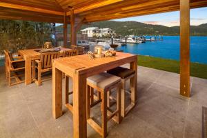 a wooden table and chairs on a patio next to the water at 23 The Cove - Whitsunday Waterfront Living in Airlie Beach
