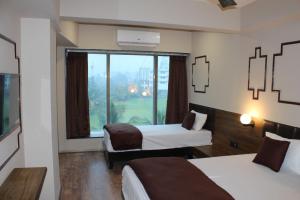 a hotel room with two beds and a large window at Crescent Rooms And Banquet in Surat