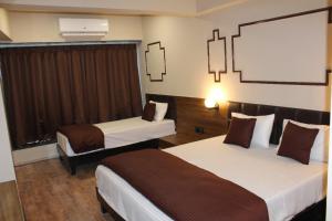 a hotel room with two beds and a window at Crescent Rooms And Banquet in Surat