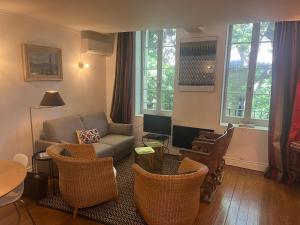 a living room with a couch and chairs and a tv at Duplex Face au Palais in Avignon
