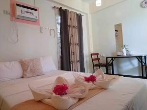 a bedroom with a white bed with red flowers on it at golden anchor lodge in Coron