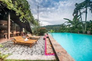 une piscine avec des bancs et des tables à côté d'une maison dans l'établissement Villa Dandan Bukit, à Gianyar