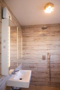 ein Badezimmer mit einem weißen Waschbecken und Holzwänden in der Unterkunft The Beach House Roof in Vila Nova De Cacela